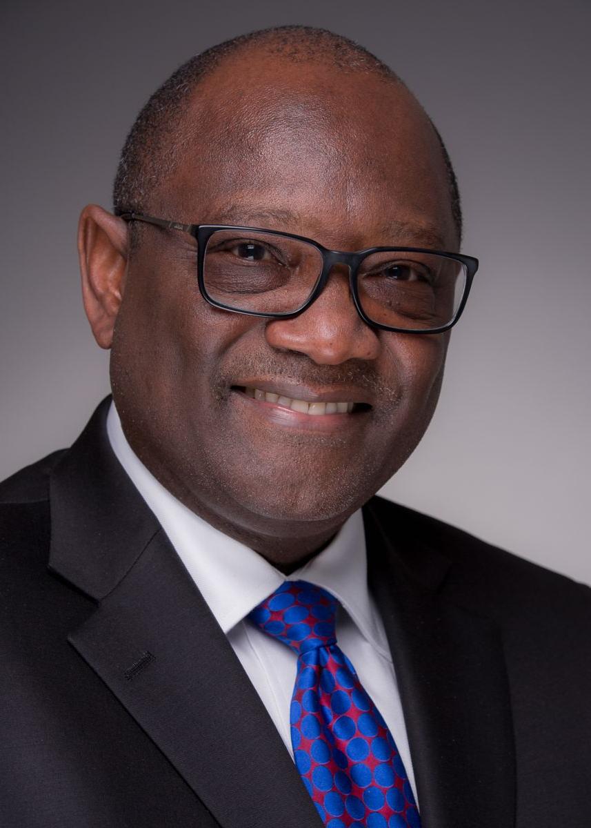 Mr. 约翰·理查森, 非裔美国男性, 戴着黑框眼镜微笑着, 一套黑色套装，配一条红色图案的蓝色领带.